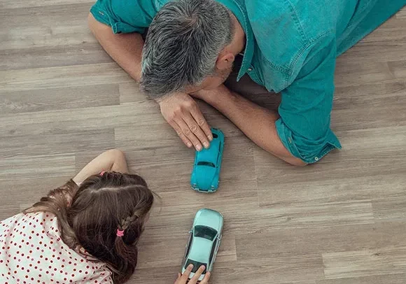 Father and daughter playing cars on luxury vinyl floor